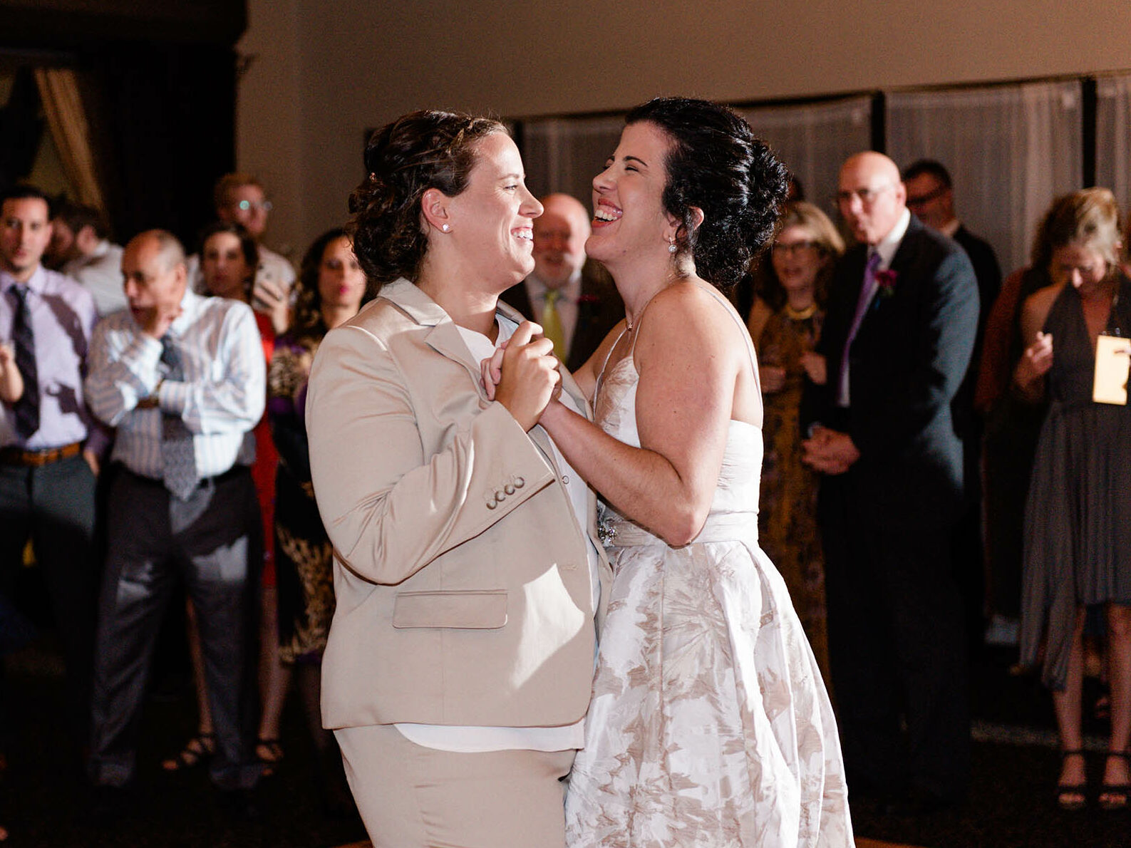 Two brides laughing and smiling during first dance