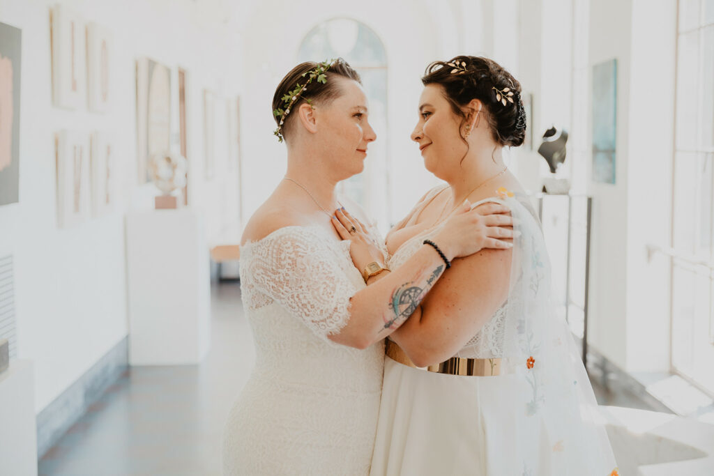 two brides embrace in art gallery