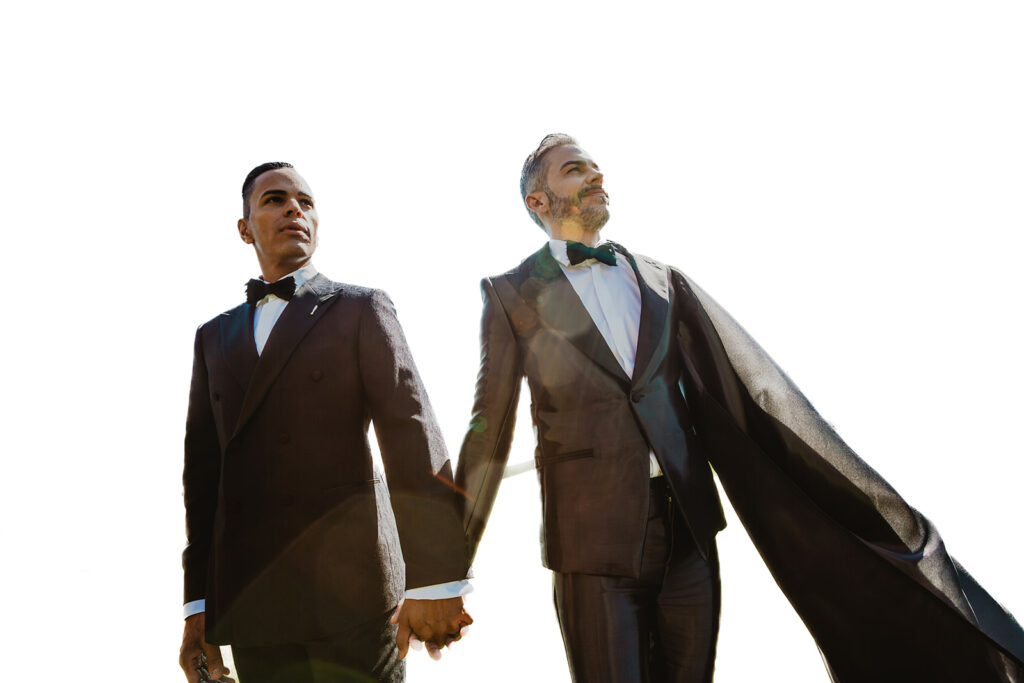 two grooms in black tuxes with cape