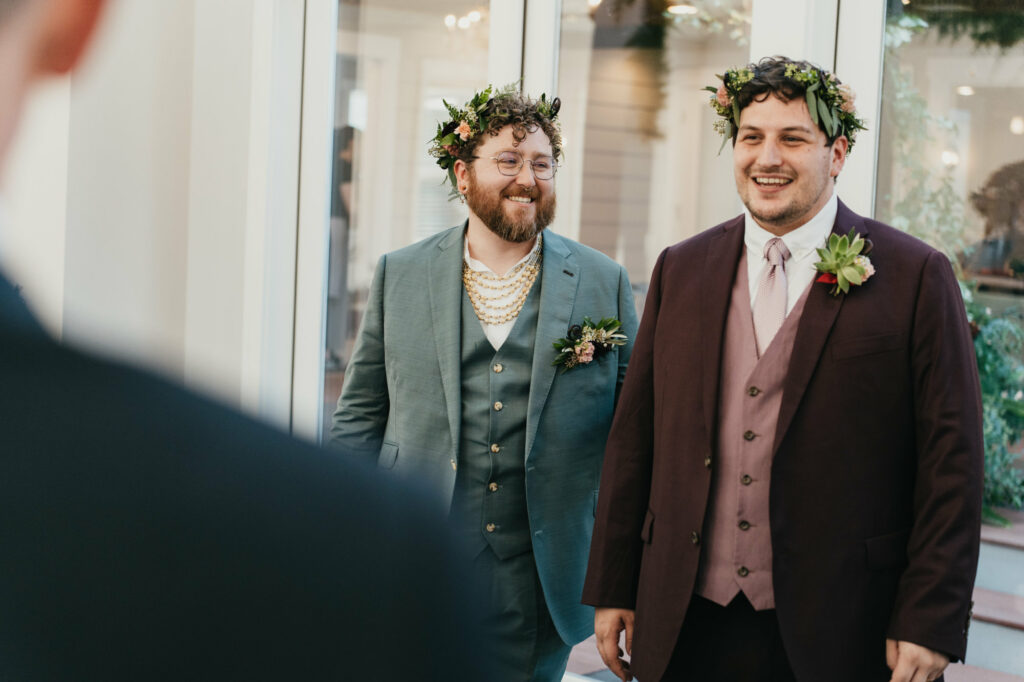 two grooms with flower crowns at wedding reception