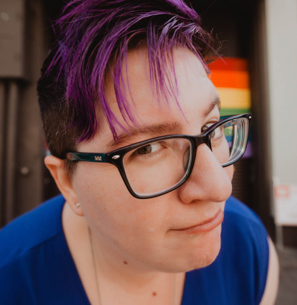 Cindy Savage, a queer wedding planner, making a funny face and wearing glasses