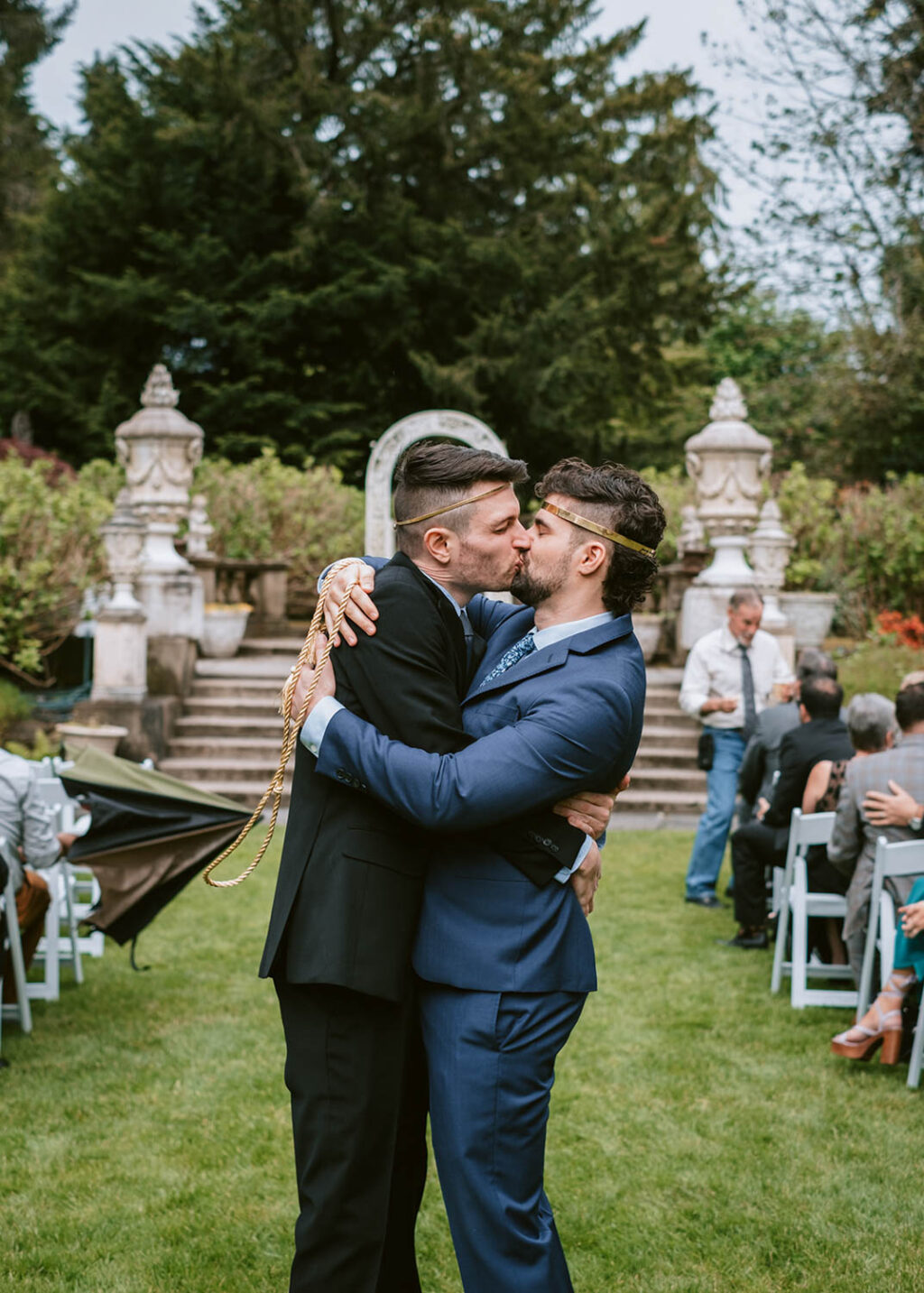 grooms kissing in wedding aisle