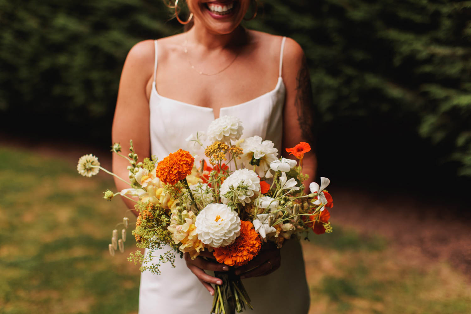 bride holding orange and white flower bouquet