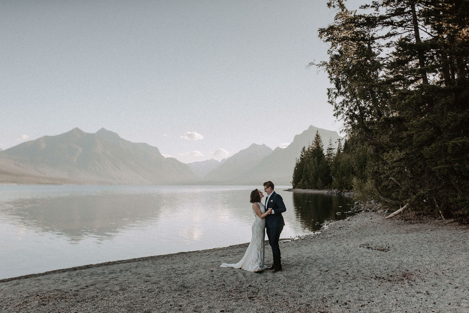 couple standing on the beach of a lake in the pacific northwest