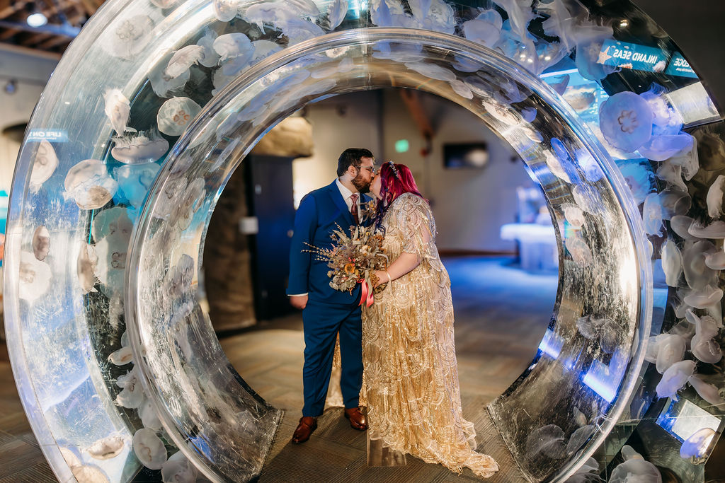 bride and groom kissing under jellyfish tank at seattle aquarium