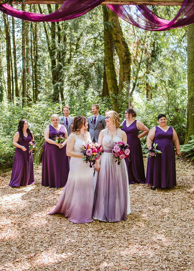 Elisa and Erin wearing purple ombre dresses and standing with wedding party