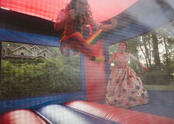 wedding couple bouncing on bouncy house at their wedding