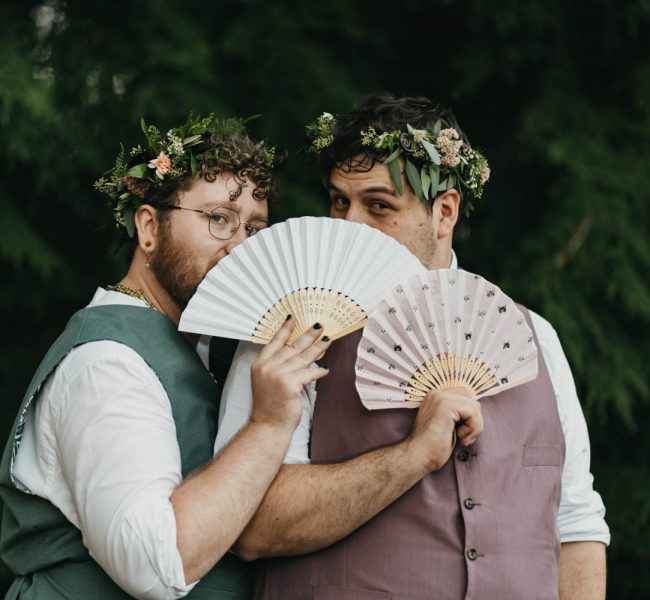 grooms standing together with paper fans and flower crowns