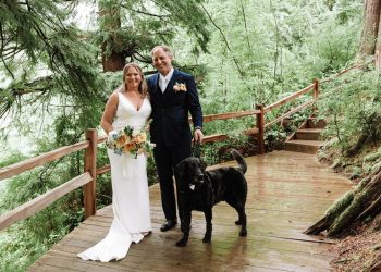 bride and groom standing with dog on wood stairs at wedding in seattle