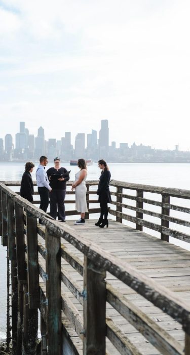 Cindy Savage marrying a couple on a dock in front of the Seattle skyline