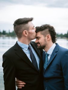 grooms kissing in front of water in Seattle