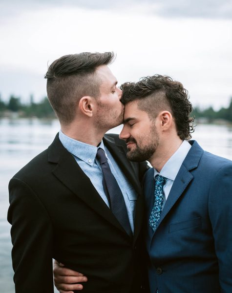 grooms kissing in front of water in Seattle