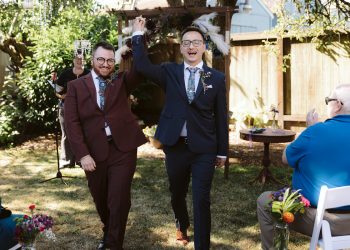 Two grooms walk down the aisle at Seattle backyard wedding