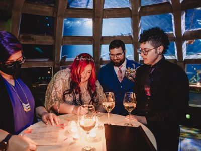 couple signing their marriage certificate at their seattle aquarium wedding with Cindy Savage looking over it